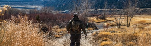 Fly Fishing carrying rod to water wearing waders