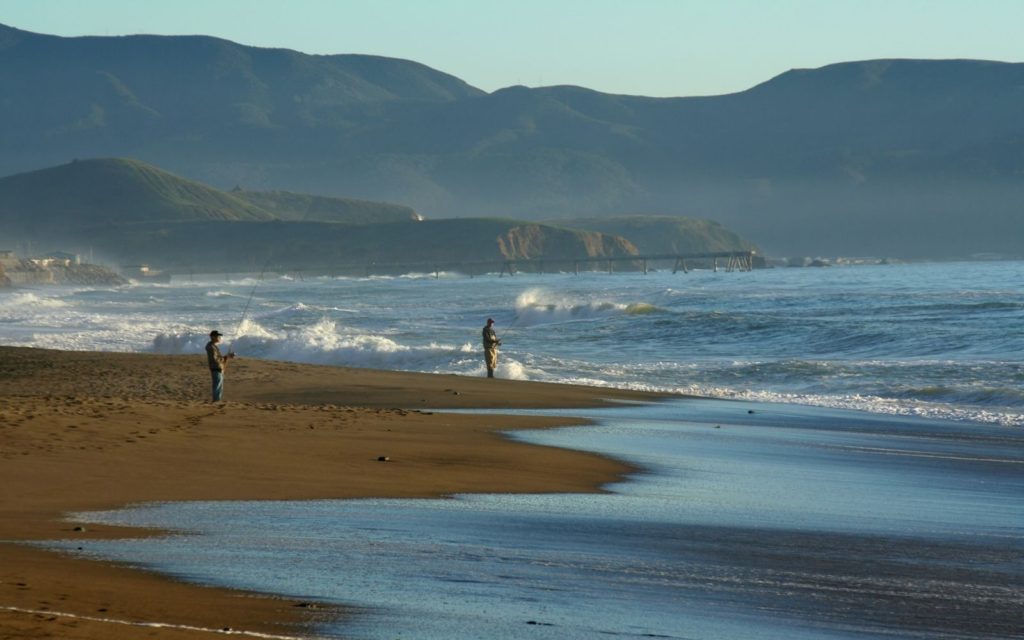 Two fly anglers surf fly fishing from a tropical beach