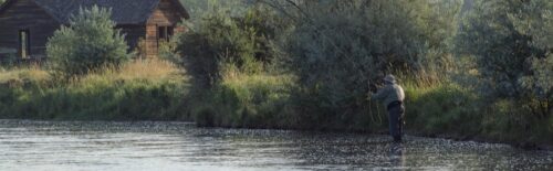 Angler casting a fly rod across a wide river
