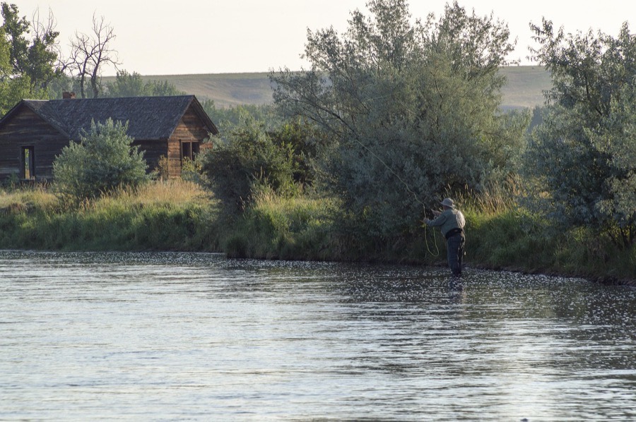 Angler casting a fly rod across a wide river