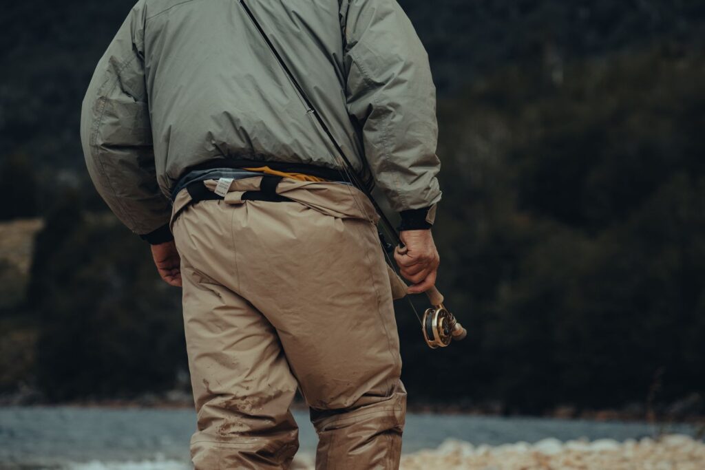 An angler carries a fly rod along a Montana river bank