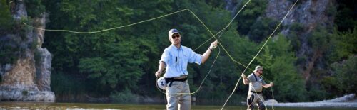 Two fly fishermen casting in the clear water of a river canyon
