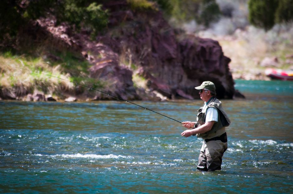 angler wading a river fly fishing with a bent rod
