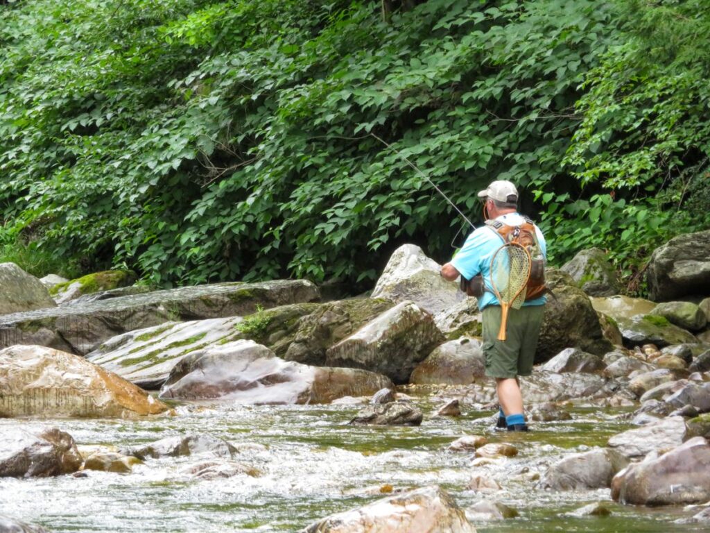 An angler working upstream with a landing net